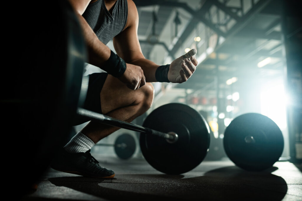 below view of unrecognizable bodybuilder preparing for deadlift in a gym.